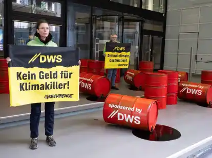 Mit roten &Ouml;lf&auml;ssern protestieren Aktivisten von Greenpeace vor der Zentrale von DWS Investment in Frankfurt gegen die Investitionspolitik des Fonds.