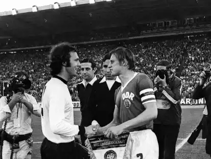 22. Juni 1974: Der Kapitän der Auswahl der Bundesrepublik, Franz Beckenbauer (links), und der Spielführer der DDR-Auswahl, Bernd Bransch, tauschen vor dem WM-Gruppenspiel in Hamburg die Wimpel ihrer Verbände.