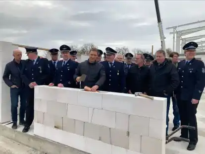 Im Beisein zahlreicher Kameraden der Feuerwehr Uplengen-Mitte setzt Uplengens B&uuml;rgermeister Heinz Trauernicht den Grundstein in Form einer &bdquo;Zeitkapsel&ldquo; f&uuml;r das neue Feuerwehrgeb&auml;ude.