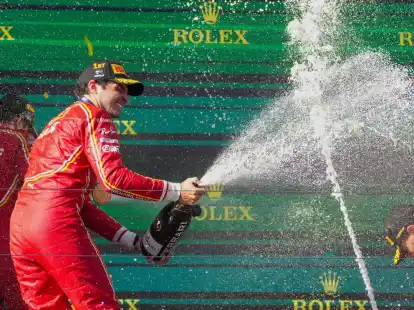 Ferrari-Pilot Carlos Sainz feiert mit Champagner seinen Sieg.