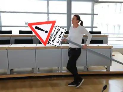 Eine Elternvertreterin der Initiative &bdquo;Bildung in Not&ldquo; geht mit einem Schild durch den Tagungsraum. Im Bezirk L&uuml;neburg gibt es &Auml;rger um die Wahl zum Landeselternrat.