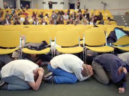 Schüler suchen bei einer Erdbebenübung Schutz unter Stühlen in der Aula. Mehr als 400 Schüler eines Aachener Gymnasiums übten, wie sie sich bei einem Erdbeben richtig verhalten sollen. (Archivbild)