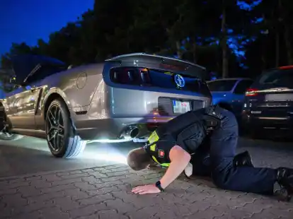 Polizisten kontrollieren ein getuntes Fahrzeug.