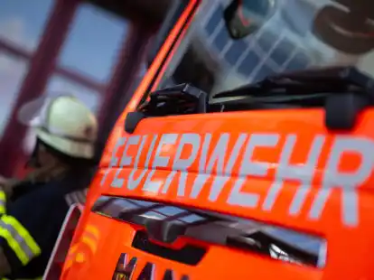 Ein Feuerwehrmann steht neben einem Einsatzfahrzeug. Wenn Rettungskr&auml;fte zu einem absichtlich falsch abgesetzten Notruf rausfahren, entstehen hohe Kosten und Menschenleben werden gef&auml;hrdet. (Symbolbild).