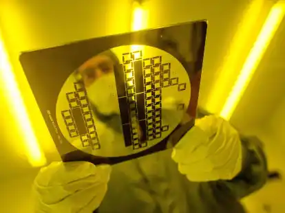 Ein Mann tr&auml;gt in einem Reinraum eine sogenannte &laquo;Maske&raquo; zur Herstellung von Halbleiterstrukturen durch den Reinraum. Deutschland hat laut Deloitte gute Voraussetzungen f&uuml;r den Aufbau einer eigenen Chip-Produktion.
