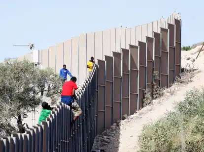 Migranten klettern &uuml;ber einen Zaun auf der Insel Lampedusa.