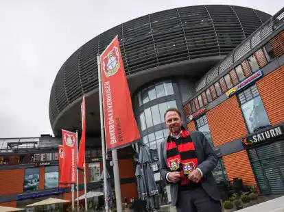 Uwe Richrath, Oberb&uuml;rgermeister von Leverkusen, steht mit einem Fanschal vor dem Rathaus.