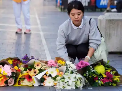Eine Frau bringt Blumen zu einer improvisierten Gedenkst&auml;tte an der Bondi Junction.