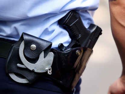 Ein Polizist trägt Handschellen und seine Dienstwaffe bei sich.