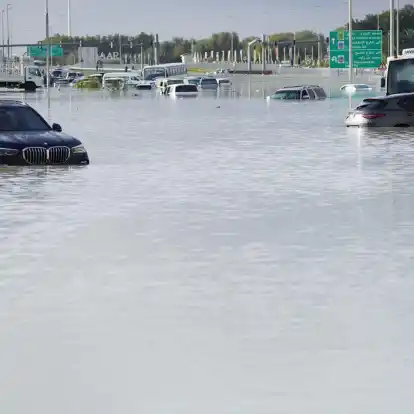 Fahrzeuge stehen verlassen im Hochwasser auf einer Hauptstraße in Dubai.