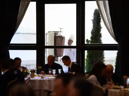 Ein Koch bereitet auf einer Terrasse des Pr&auml;sidialpalasts D&ouml;nerfleisch vom Spie&szlig; zu.