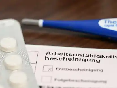 Ein Fieberthermometer und Medikamente liegen bei einer ärztlichen Arbeitsunfähigkeitsbescheinigung. In Niedersachsen war 2023 der Kranenstand weiterhin hoch.