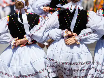Mädchen in traditionellen Trachten halten sich bei einem Tanz während des „Vynohradna Loza“ (Weinreben-Festivals) in der Ukraine an den Händen.