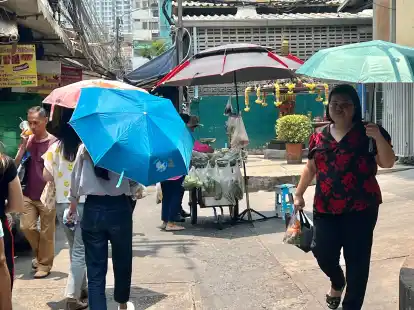 Menschen schützen sich in Bangkok mit Schirmen vor der extremen Hitze und vor der Sonne. Nicht nur in Thailand, sondern auch auf den Philippinen leiden die Menschen derzeit unter den hohen Temperaturen.
