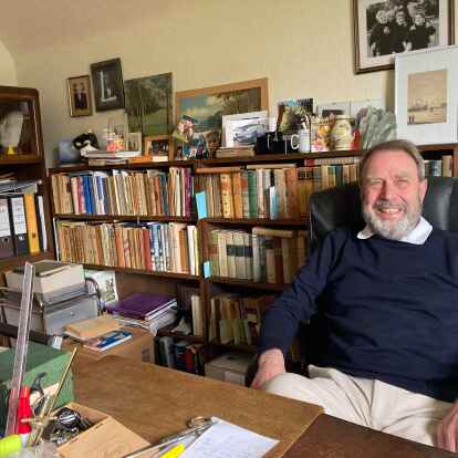 Dirk Hinrichs ist  Verwalter des Nachlasses von August Hinrichs. Im Hintergrund sind die verschiedenen Ausgaben der Werke seines Großvaters und Heimatschriftstellers zu sehen.