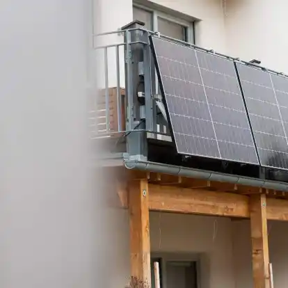 Eine Balkonsolaranlage hängt an einem Wohnhaus. Mit der richtigen Ausrichtung kann man kräftig Stromkosten einsparen.
