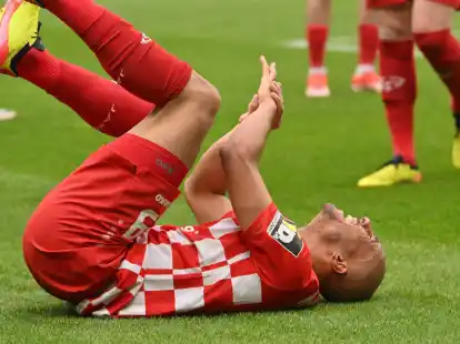 Der Mainzer Karim Onisiwo liegt mit einer verletzten Hand am Boden.