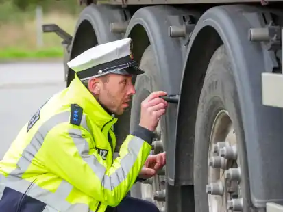 Ein Polizeibeamter prüft den technischen Zustand eines LKW.