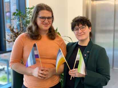 Hanna Varrelmann (links) und Moss Bohrer von der Oldenburger Gruppe „Aces & Aros“ halten asexuelle und aromantische Pride-Flaggen.