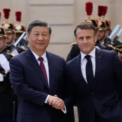 Der französische Präsident Emmanuel Macron (r) begrüßt Chinas Präsident Xi Jinping vor ihrem Treffen im Elysee-Palast.
