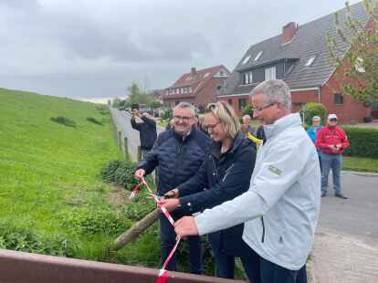Ortsvorsteher Simon Lübben (links) und Bürgermeister Rolf Claußen unterstützen Kim Hillrichs bei der offiziellen Eröffnung der neuen Deichtreppe.