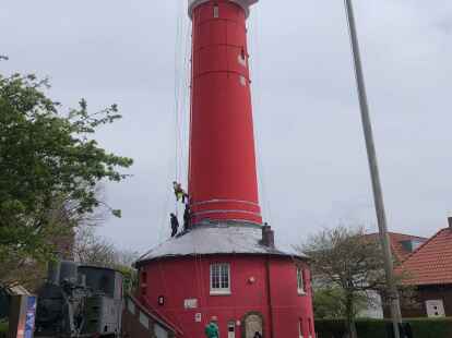 Der Alte Leuchtturm auf Wangerooge ist verschönert worden: Hier bringen Industriekletterer ein neues Fallrohr an.