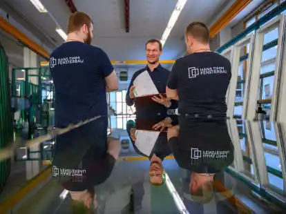 An einem fertigen Fenster im Haus haben viele Menschen mitgewirkt: Mathias Schulz, Tischlermeister und Produktionsleiter bei Hans Timm Fensterbau, spricht in der Glaserei mit seinen Kollegen.