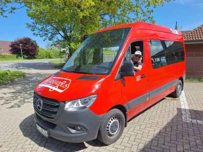 Bitte einsteigen: Der Bürgerbus des Mobilitätsvereins Wangerland ist mit seiner roten Lackierung nicht zu übersehen. Aus dem Fenster schaut Petra Schmähling-Gruß.