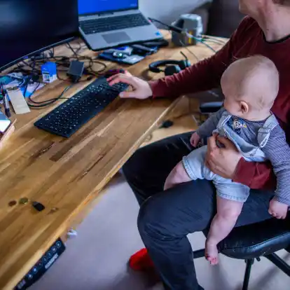 Ein junger Vater im Home-Office mit seinem sechs Monate alten Sohn.