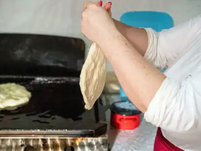 Aus der faustgro&szlig;en Teigkugel wird der Teig f&uuml;r den L&aacute;ngos mit der Hand auf Tellergr&ouml;&szlig;e platt gestrichen.