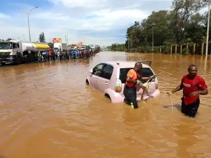 Menschen in Nairobi, die im Hochwasser ein Auto ziehen.