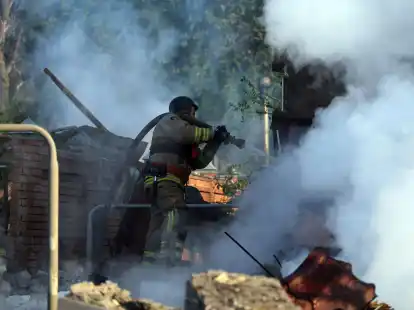 Nach einem russischen Angriff bei Charkiw versuchen ukrainische Rettungskräfte ein Feuer zu löschen.