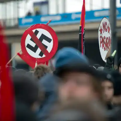 Teilnehmer einer Demonstration unter dem Motto &bdquo;Mit Mut, Respekt und Toleranz gegen Rechtsextremismus&ldquo; halten ein Schild mit einem durchgestrichenen Hakenkreuz.