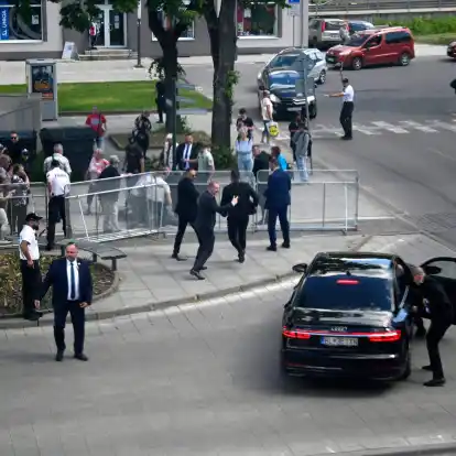 Leibwächter bringen den slowakischen Ministerpräsidenten Robert Fico in einem Auto vom Ort des Geschehens in Sicherheit.