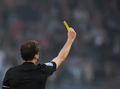 Ein schiedsrichter zeigt einem Spieler die Gelbe Karte.