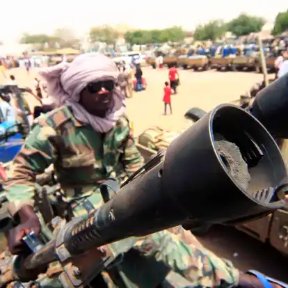 Ein Milizionär sitzt neben militärischer Ausrüstung, die angeblich während eines Gefechts im umkämpften Gebiet in Süd-Darfur erbeutet wurde.
