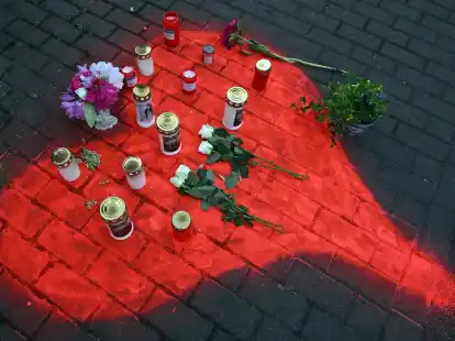 Kerzen und Blumen liegen in einem auf das Pflaster gesprühten roten Herzen in Düsseldorf nach dem mörderischen Brandanschlag.