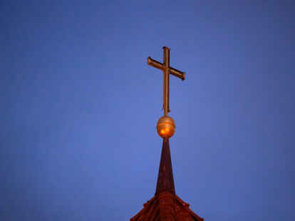 Ein Kreuz steht auf der Kirchturmspitze einer evangelischen Kirche in der Region Hannover.  (Symbolbild)