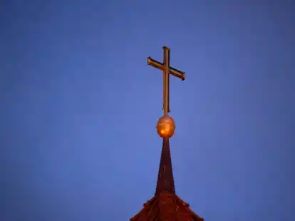 Ein Kreuz steht auf der Kirchturmspitze einer evangelischen Kirche in der Region Hannover.  (Symbolbild)