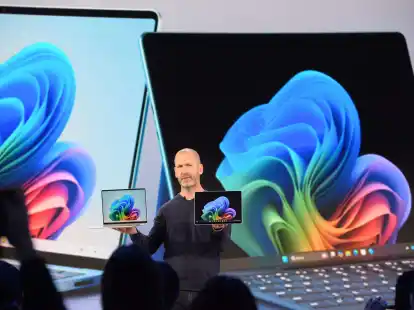 Microsoft-Manager Brett Ostrum zeigt ein Notebook und ein Tablet der hauseigenen Marke Surface, die auf den Einsatz Künstlicher Intelligenz ausgerichtet sind. Microsoft will Windows-PCs fit für die KI-Ära machen.