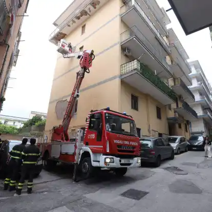 Von einem Hubwagen aus inspiziert ein Feuerwehrmann Schäden an einem Gebäude.