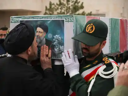 Ein iranischer Geistlicher küsst den Sarg des verstorbenen Präsidenten Ebrahim Raisi während des Trauerzuges.