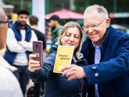 Selfies sind gefragt: Stephan Weil (SPD, re.), Ministerpräsident von Niedersachsen, nimmt vor dem Bahnhof in Hannover ein Foto mit einer Passantin und einem Heft mit dem Grundgesetz auf.