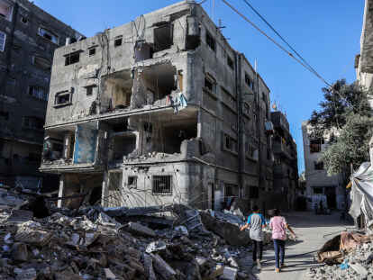 14. Mai 2024: Vertriebene palästinensische Kinder aus der Stadt Rafah, die vor den Kämpfen fliehen, gehen während der anhaltenden Kämpfe zwischen Israel und der Hamas an von israelischen Kampfflugzeugen zerstörten Gebäuden vorbei. Auslöser der israelischen Angriffe in Gaza ist der Überfall der Terrororganisation Hamas am 7. Oktober 2023 im Süden Israels, bei dem 1200 Menschen getötet und viele mehr in den Gaza-Streifen verschleppt wurden. +++ dpa-Bildfunk +++