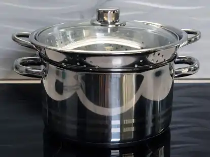 Auf dem offenen Kochtopf mit den Karotten wird ein Sieb platziert, die Brokkoli-R&ouml;schen darin hineingelegt. Darauf kommt ein Deckel.