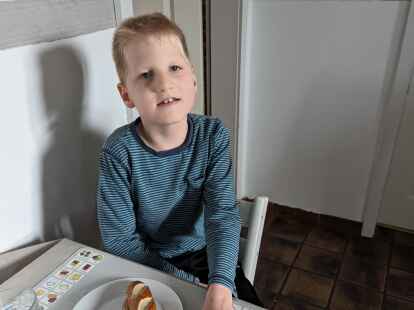 Theis (9) hat eine geistige Behinderung, die mit frühkindlichem Autismus einhergeht. Zum Kommunizieren nutzt er Hilfsmittel wie ein Tischset mit Piktogrammen.