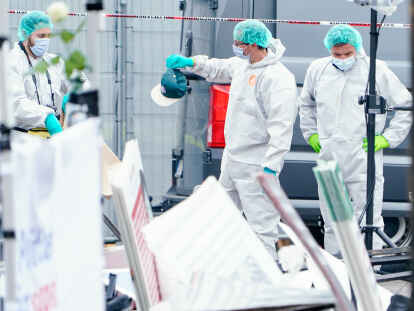 Messerangriff in Mannheim: Mitarbeiter der Spurensicherung halten an einem Stand auf dem Marktplatz eine Kappe in den Händen.