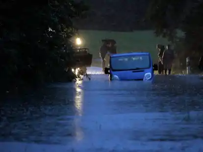 Ein Fahrzeug steht in Lindau in Bayern auf einer &uuml;berfluteten Stra&szlig;e am Bodensee.