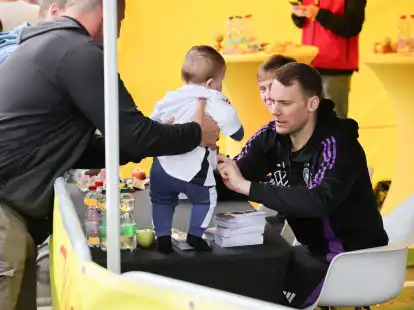Torwart Manuel Neuer (r.) und Maximilian Beier geben Autogramme. Neuer unterschreibt hier auf einem Baby-Trikot.