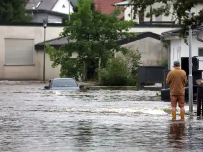 Ein Mann l&auml;uft in einem vom Hochwasser der Mindel &uuml;berschwemmten Wohngebiet. +++ dpa-Bildfunk +++